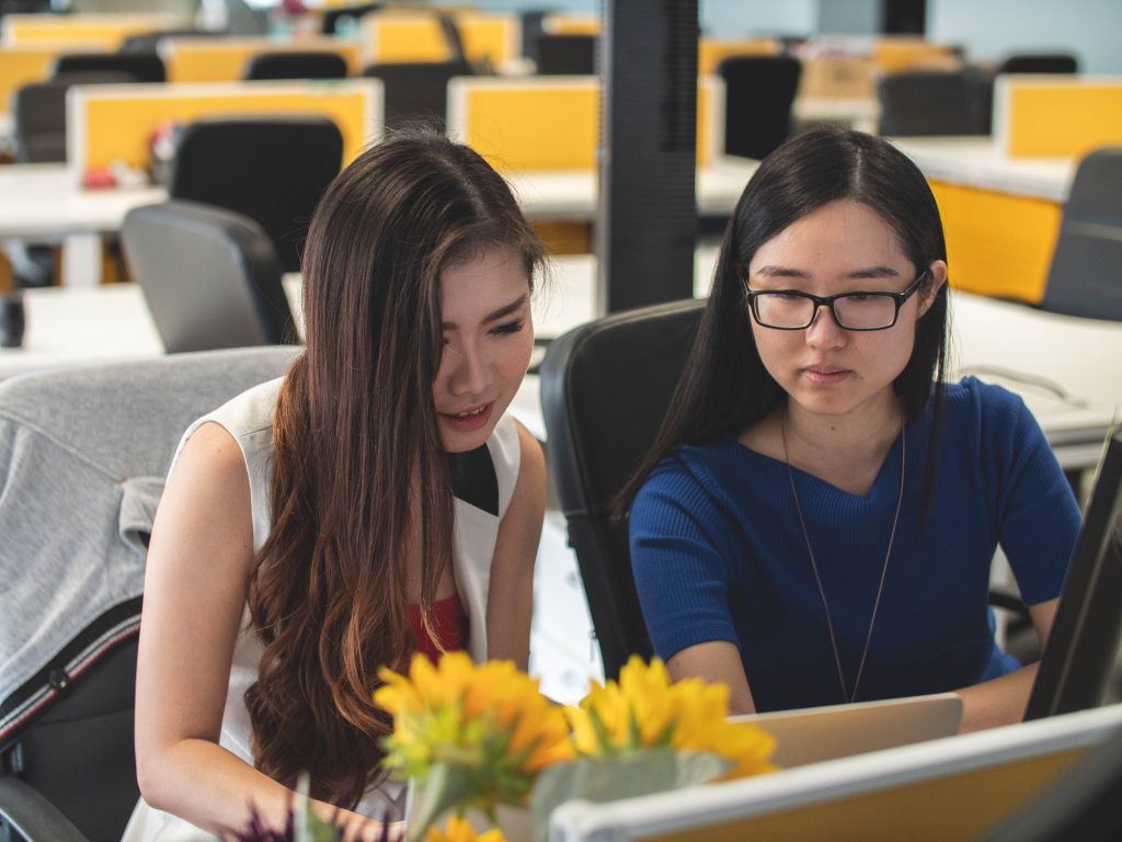 two girls in a computer lab looking at a laptop