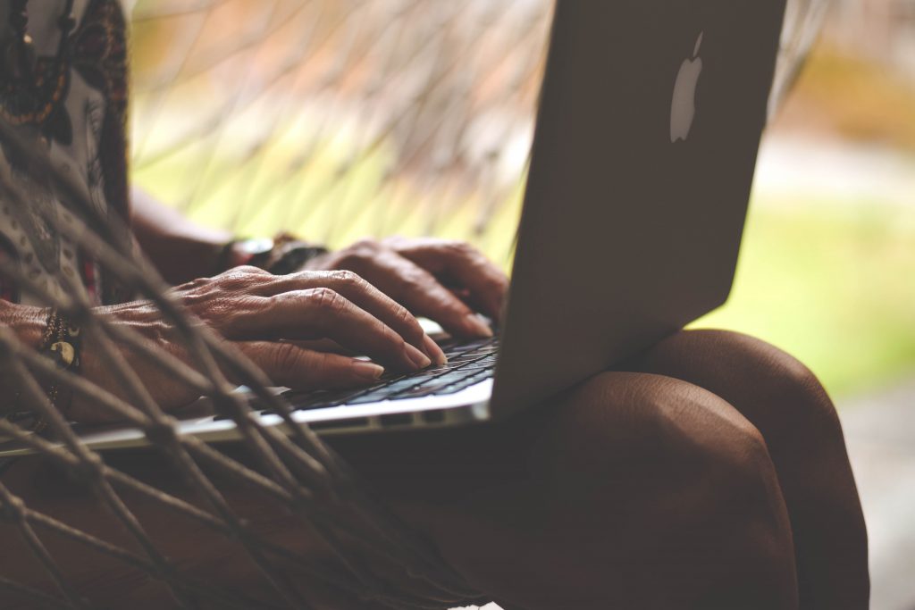 person using a laptop outdoors in a hammock